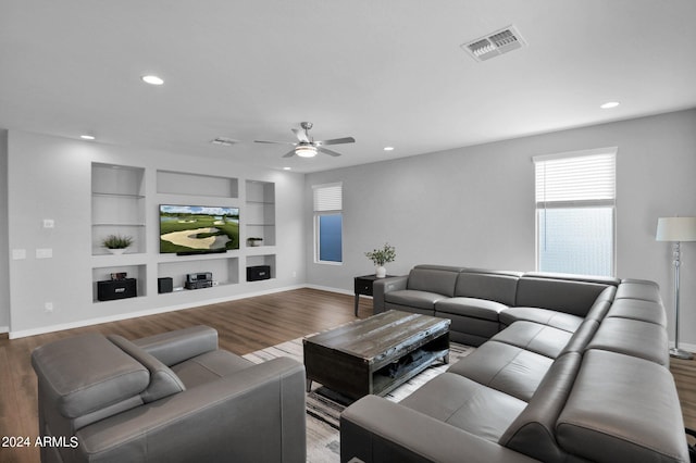 living room featuring wood-type flooring, built in shelves, and ceiling fan