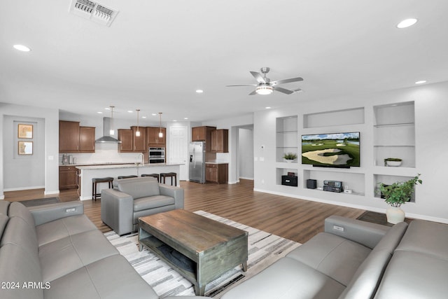 living room featuring light hardwood / wood-style flooring, built in shelves, and ceiling fan