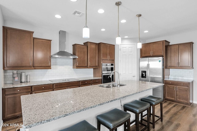 kitchen with dark hardwood / wood-style floors, sink, wall chimney range hood, appliances with stainless steel finishes, and decorative light fixtures