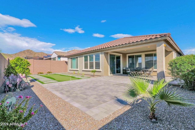 back of property with a mountain view and a patio area