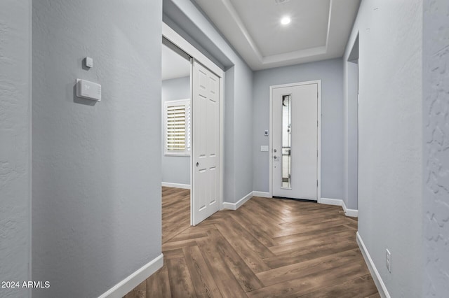 entryway with a raised ceiling, dark parquet flooring, and a barn door