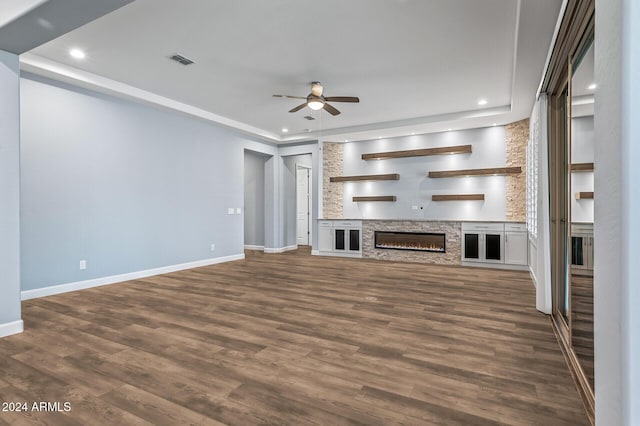 unfurnished living room with a fireplace, dark hardwood / wood-style flooring, and ceiling fan