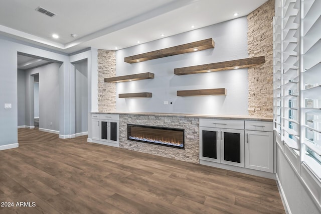 kitchen featuring white cabinets, a stone fireplace, and dark wood-type flooring