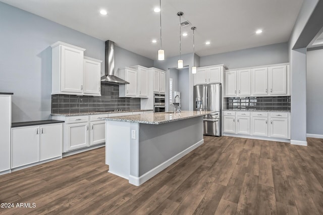 kitchen with white cabinetry, stainless steel appliances, wall chimney range hood, and decorative light fixtures