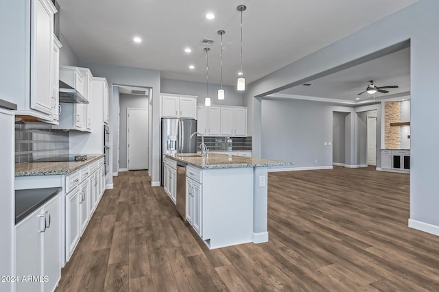 kitchen with a center island with sink, white cabinets, hanging light fixtures, and tasteful backsplash