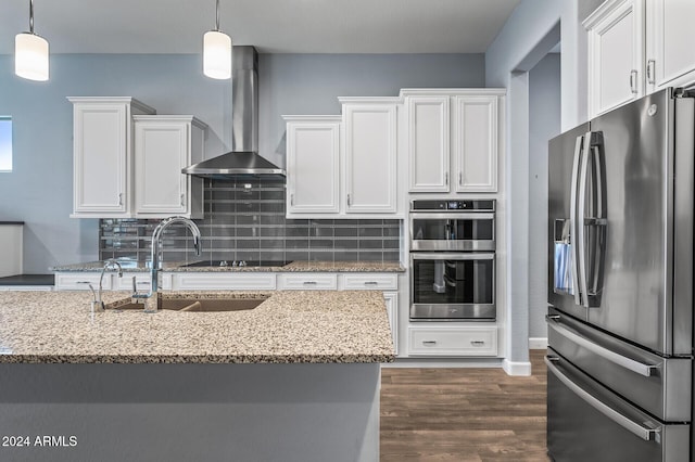 kitchen with white cabinetry, light stone countertops, stainless steel appliances, and wall chimney range hood