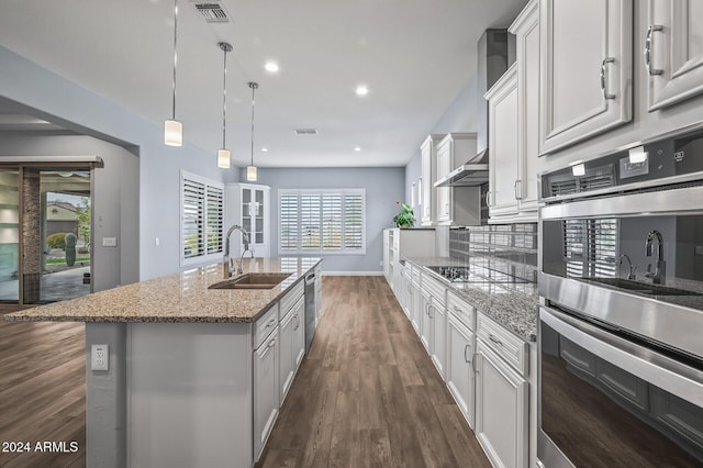 kitchen with a center island with sink, sink, hanging light fixtures, white cabinetry, and stainless steel appliances