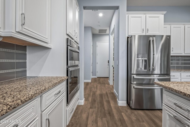 kitchen with decorative backsplash, white cabinets, stone countertops, and appliances with stainless steel finishes