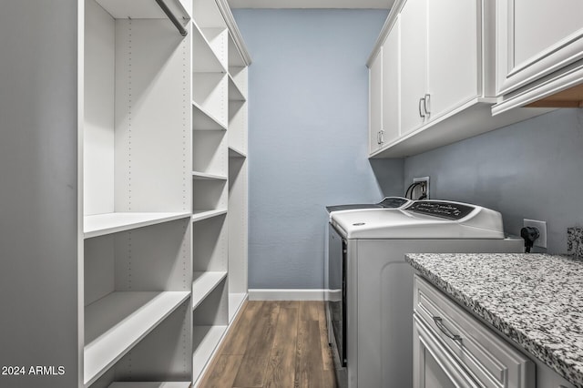 clothes washing area with cabinets, dark hardwood / wood-style floors, and washer and clothes dryer