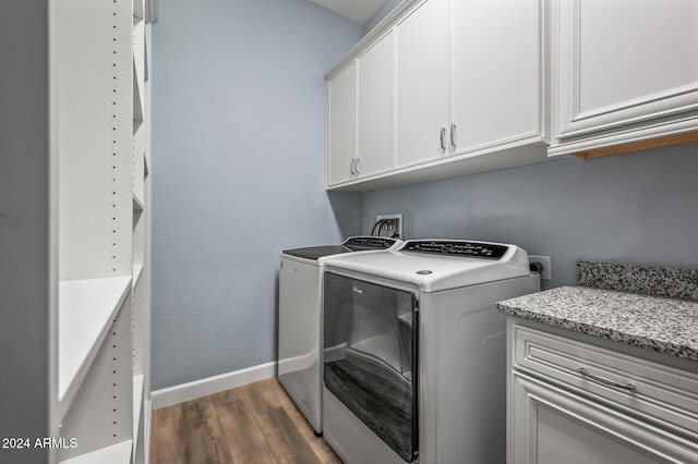 laundry room with washing machine and clothes dryer, dark hardwood / wood-style flooring, and cabinets