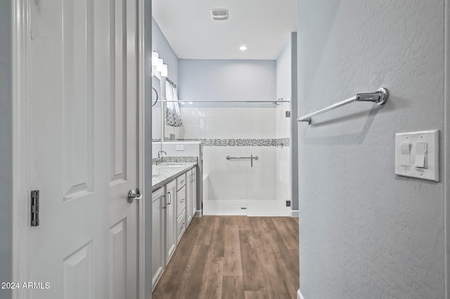 bathroom with hardwood / wood-style flooring, vanity, and a tile shower