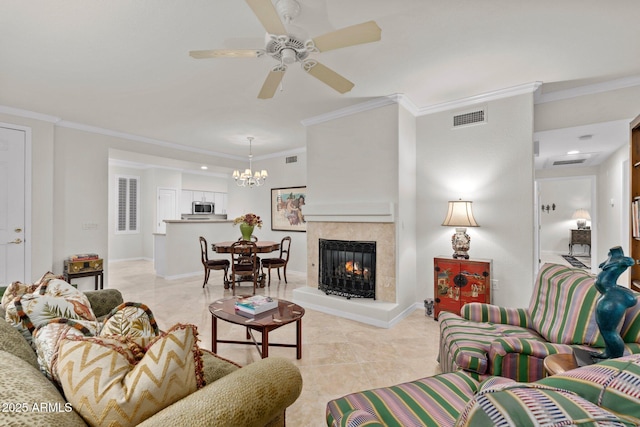 living room with a tiled fireplace, crown molding, ceiling fan with notable chandelier, and light tile patterned floors