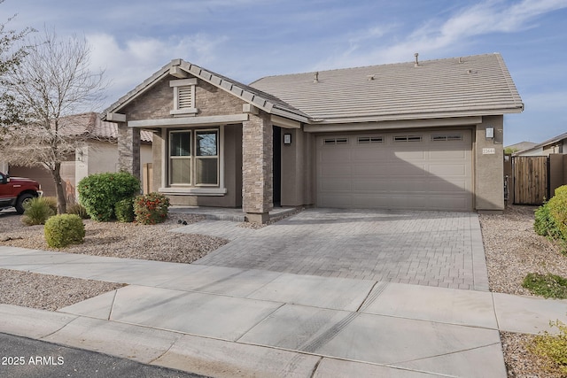 ranch-style home featuring decorative driveway, an attached garage, fence, and stucco siding