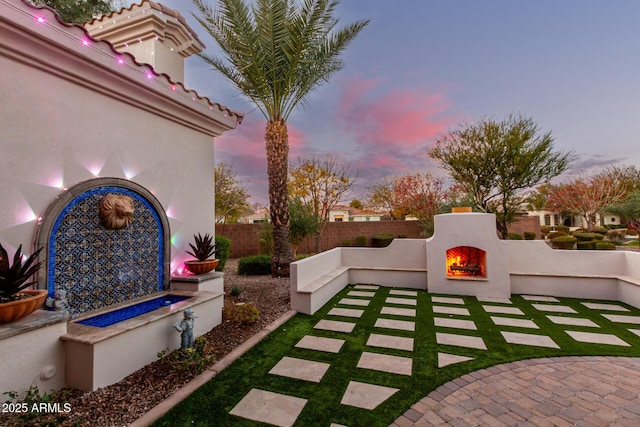 patio terrace at dusk featuring exterior fireplace