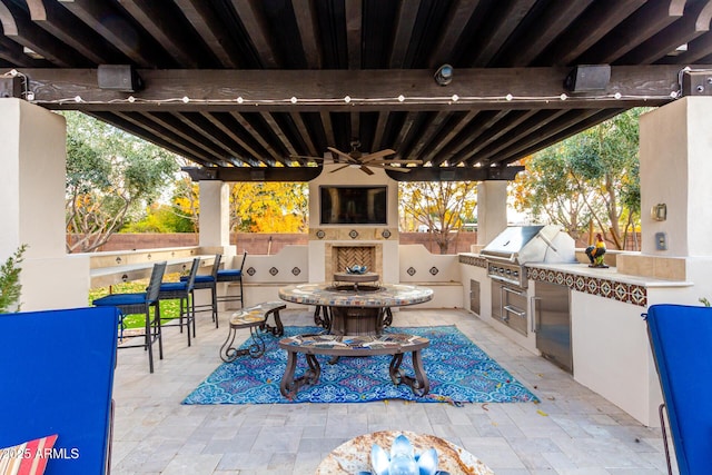 view of patio / terrace featuring area for grilling, an outdoor bar, ceiling fan, and an outdoor kitchen