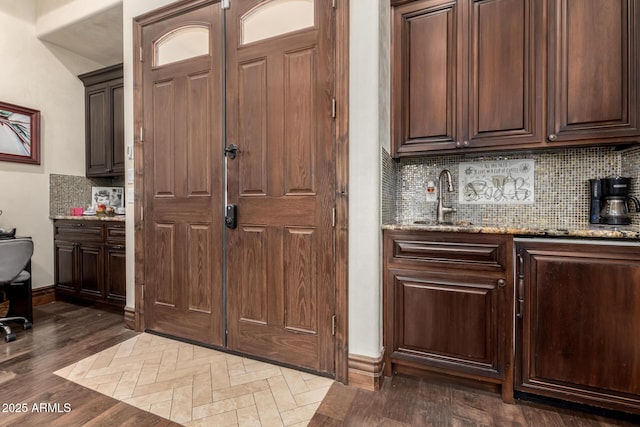 kitchen with dark brown cabinetry, sink, and light stone counters