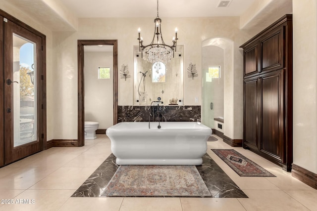 bathroom with a healthy amount of sunlight, a tub to relax in, tile patterned floors, and toilet