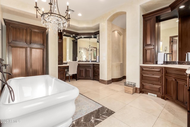 bathroom featuring an inviting chandelier, tile patterned floors, vanity, and a bathtub