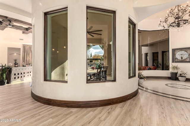 hall featuring an inviting chandelier, light hardwood / wood-style flooring, and beamed ceiling