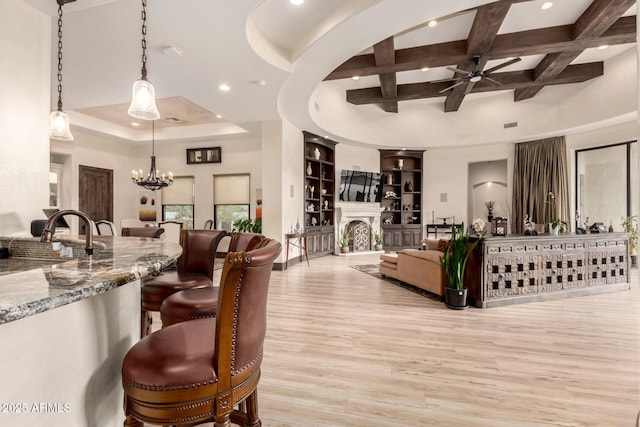 interior space featuring coffered ceiling, light hardwood / wood-style flooring, pendant lighting, beam ceiling, and light stone countertops