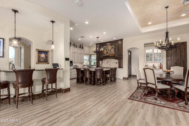 dining space featuring an inviting chandelier, plenty of natural light, and light wood-type flooring