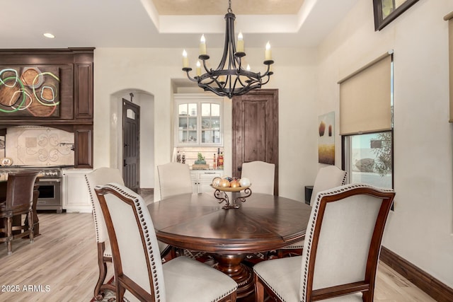 dining area featuring a tray ceiling, light hardwood / wood-style flooring, and a chandelier