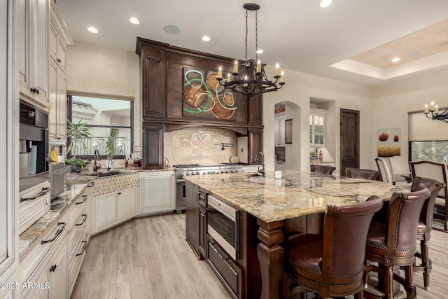 kitchen featuring appliances with stainless steel finishes, a breakfast bar, sink, a large island, and a notable chandelier