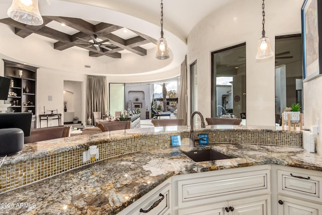 kitchen featuring pendant lighting, white cabinetry, coffered ceiling, and sink