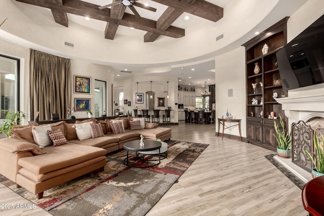 living room with light hardwood / wood-style flooring, ceiling fan, beam ceiling, a high ceiling, and coffered ceiling