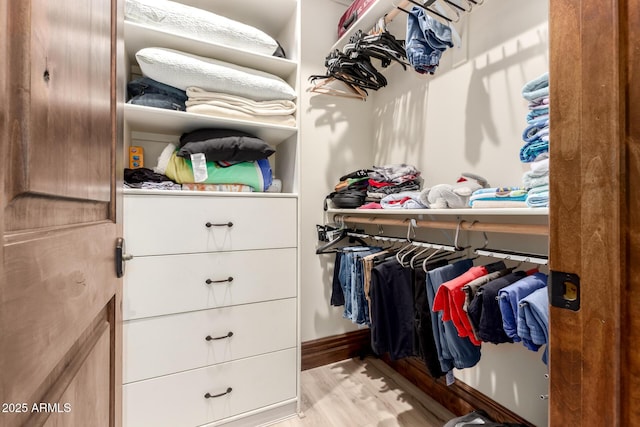 walk in closet with light hardwood / wood-style floors