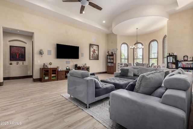 living room with ceiling fan with notable chandelier and light hardwood / wood-style floors