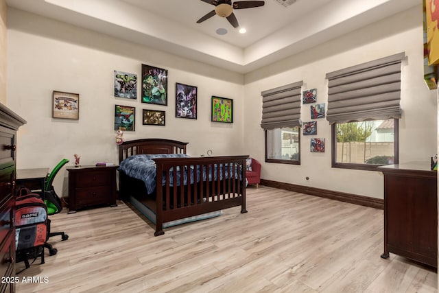 bedroom featuring a tray ceiling, ceiling fan, and light hardwood / wood-style flooring