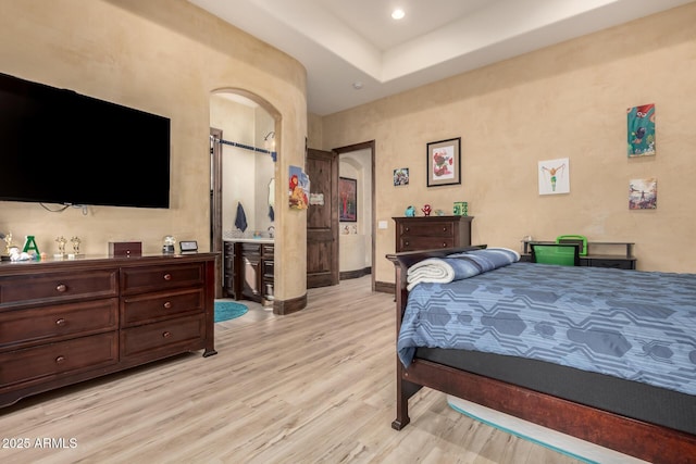 bedroom featuring a tray ceiling and light hardwood / wood-style flooring