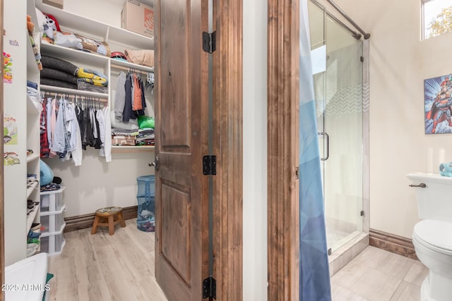 bathroom with hardwood / wood-style floors, toilet, and walk in shower