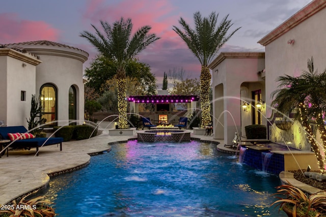 pool at dusk with a patio area and an outdoor fire pit