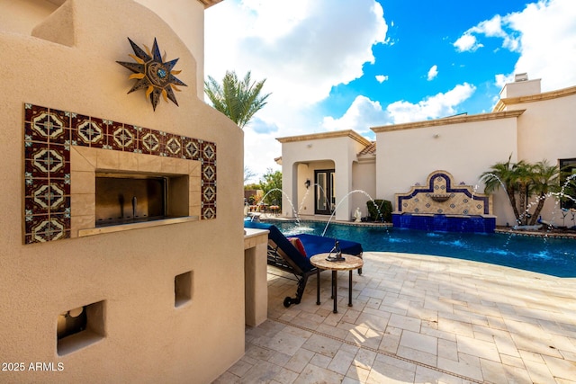 view of pool with a tile fireplace, a patio, and pool water feature