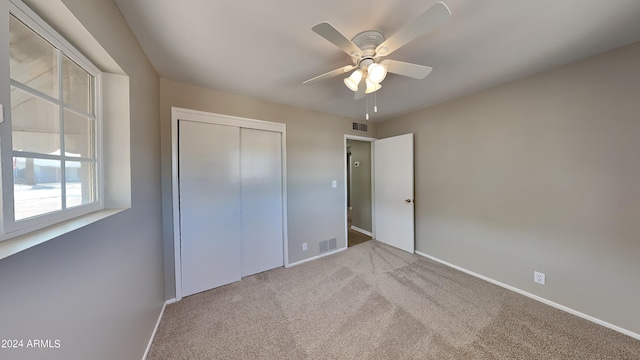 unfurnished bedroom featuring ceiling fan, light colored carpet, and a closet