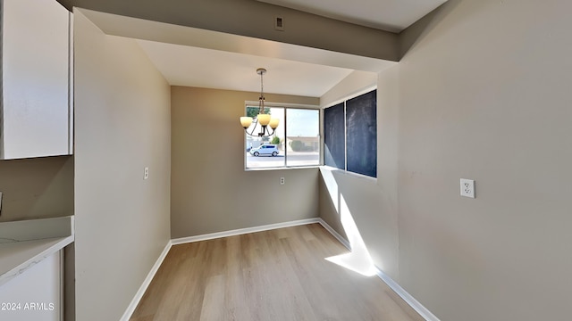 unfurnished dining area with light hardwood / wood-style floors and an inviting chandelier