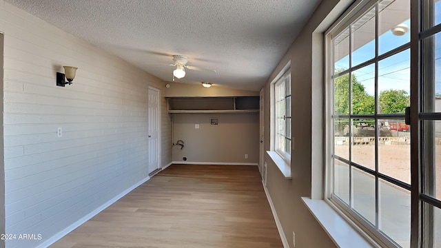 interior space featuring a textured ceiling, plenty of natural light, lofted ceiling, and light hardwood / wood-style flooring