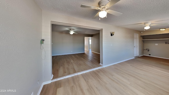 unfurnished room with ceiling fan, light hardwood / wood-style flooring, brick wall, and a textured ceiling