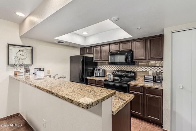 7777 E Main St Unit 143, Scottsdale, AZ 85251 - kitchen with black appliances, dark brown cabinetry, light tile patterned floors, a tray ceiling, and decorative backsplash