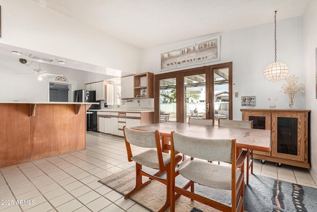 dining room with a towering ceiling, light tile patterned floors, ceiling fan, and french doors