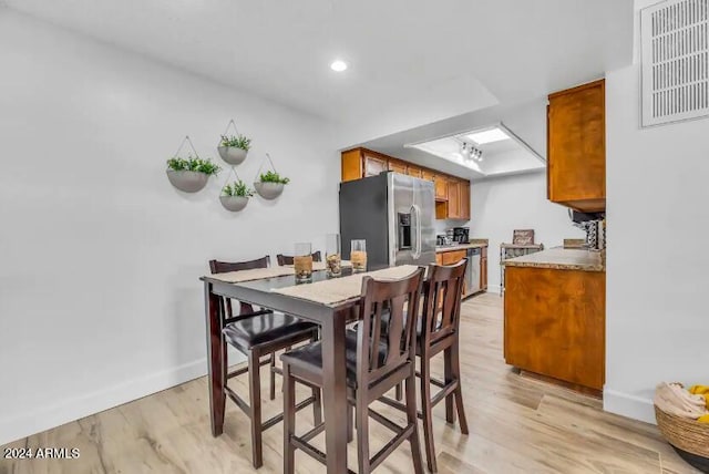 dining area featuring a skylight and light hardwood / wood-style flooring