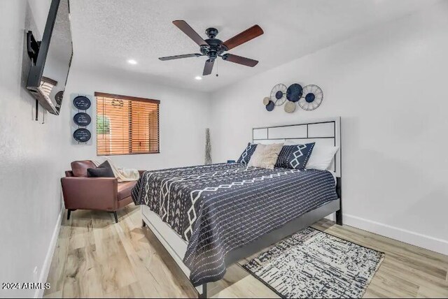 bedroom featuring ceiling fan, light hardwood / wood-style flooring, and a textured ceiling