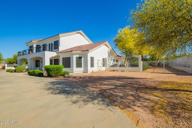 2075 W Silverlode Dr, Wickenburg, AZ 85390 - back of house featuring a tiled roof, stucco siding, and a balcony