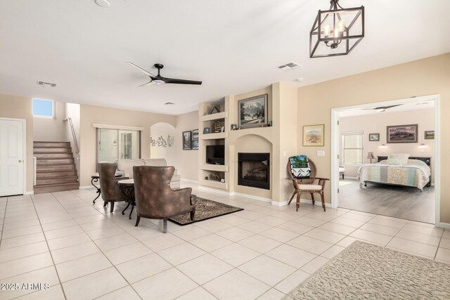2075 W Silverlode Dr, Wickenburg, AZ 85390 - living room featuring stairway, ceiling fan, light tile patterned floors, a fireplace, and built in features