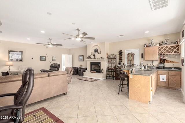 2075 W Silverlode Dr, Wickenburg, AZ 85390 - living room with bar with sink, ceiling fan, light tile patterned floors, recessed lighting, and a fireplace with raised hearth