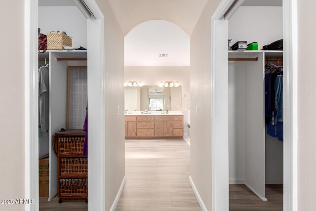 2075 W Silverlode Dr, Wickenburg, AZ 85390 - corridor with light wood-style flooring, arched walkways, and baseboards