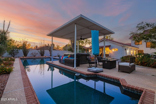 2075 W Silverlode Dr, Wickenburg, AZ 85390 - pool at dusk featuring a patio area, a fenced backyard, ceiling fan, a hot tub, and an outdoor hangout area