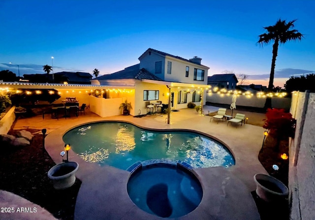 pool at dusk featuring an in ground hot tub and a patio